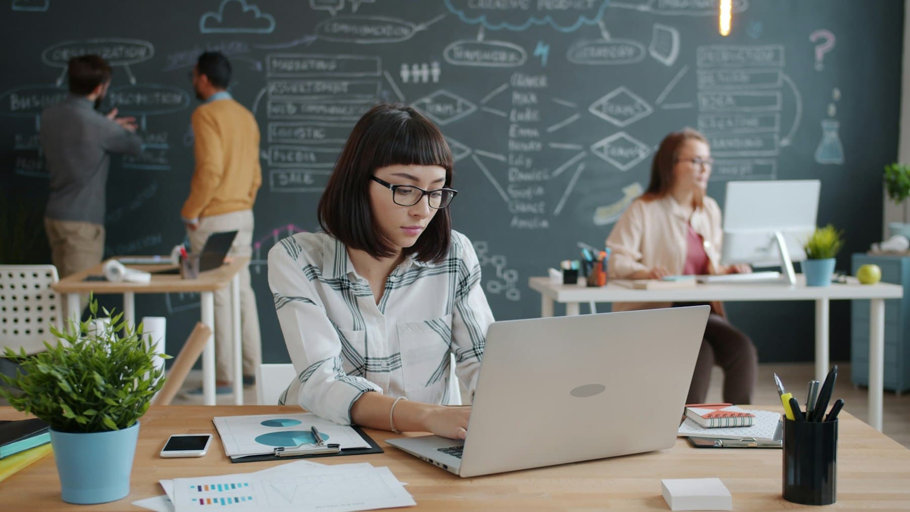 Colleagues collaborating over laptops in an open-plan studio